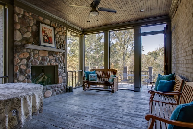 sunroom / solarium with a healthy amount of sunlight, a fireplace, ceiling fan, and wooden ceiling