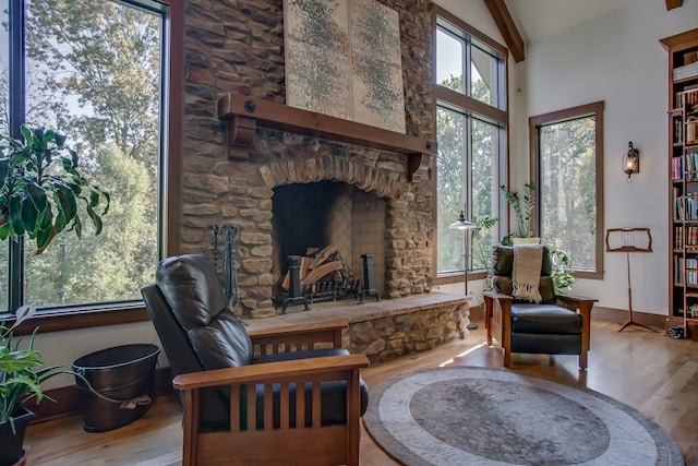 sitting room featuring hardwood / wood-style flooring, a stone fireplace, and vaulted ceiling