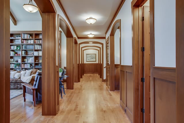 corridor with built in features, light hardwood / wood-style floors, and ornamental molding