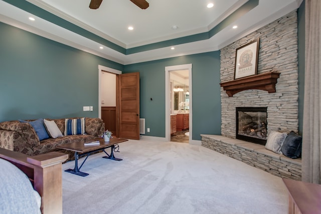 carpeted living room with ceiling fan, a raised ceiling, and a fireplace