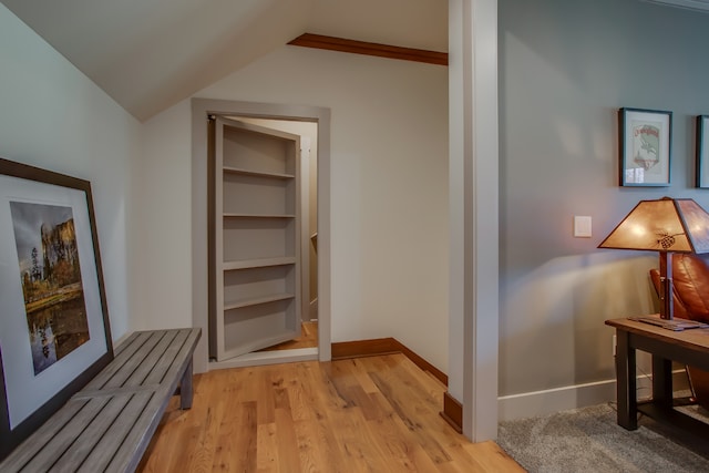 hallway featuring light hardwood / wood-style floors, built in features, and lofted ceiling