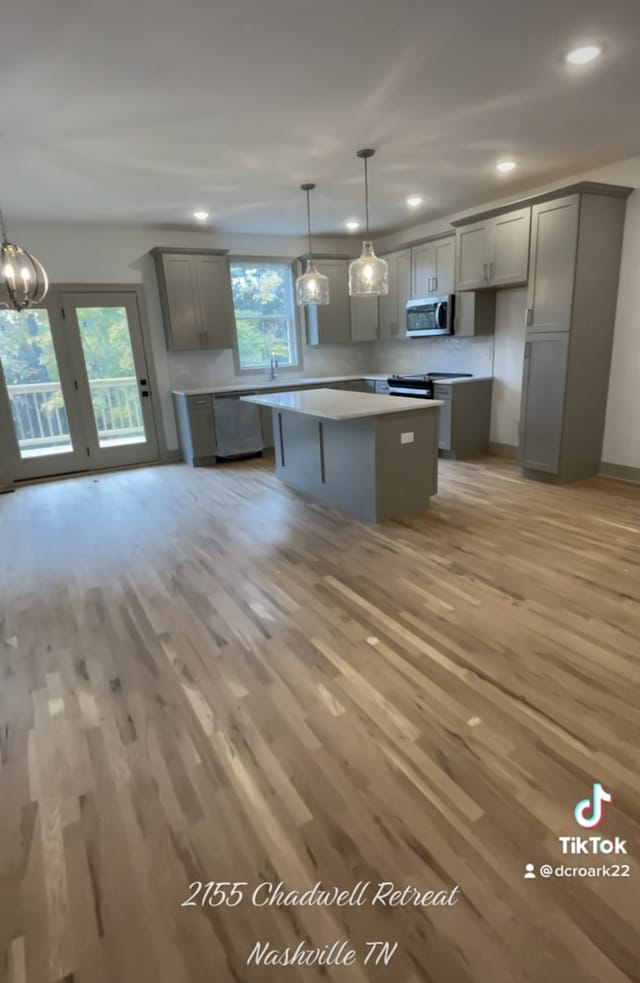 kitchen featuring gray cabinets, a kitchen island, appliances with stainless steel finishes, and pendant lighting