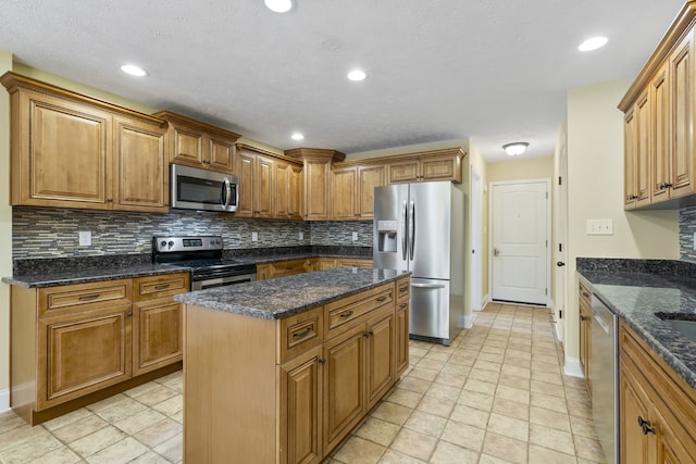 kitchen with stainless steel appliances, dark stone counters, a kitchen island, backsplash, and a textured ceiling