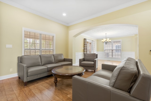 living room with light wood-type flooring, a notable chandelier, and crown molding