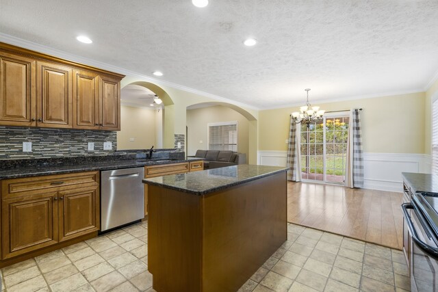 kitchen featuring crown molding, stainless steel appliances, light wood-type flooring, backsplash, and a center island