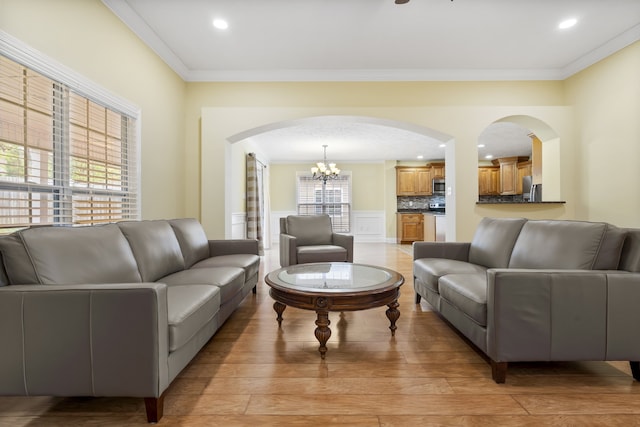 living room featuring an inviting chandelier, plenty of natural light, light hardwood / wood-style flooring, and crown molding