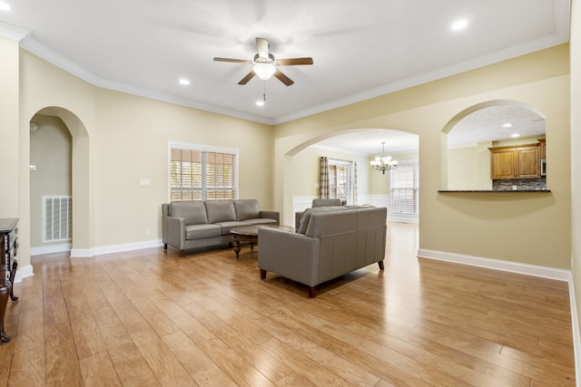 living room with ceiling fan with notable chandelier, light hardwood / wood-style floors, and crown molding