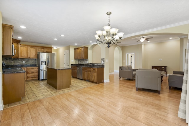 kitchen featuring stainless steel appliances, a kitchen island, crown molding, pendant lighting, and light wood-type flooring