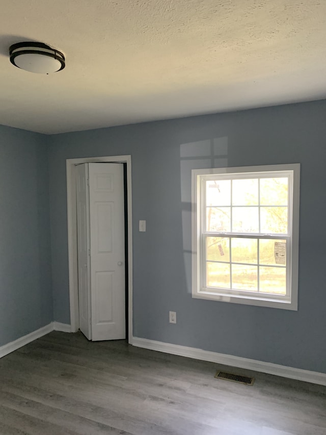 unfurnished room with a textured ceiling and hardwood / wood-style flooring