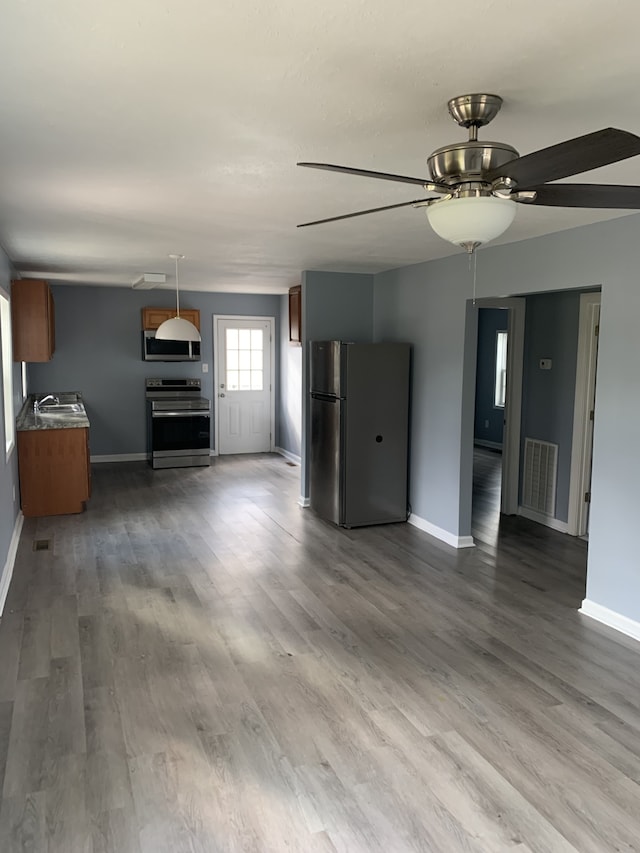 unfurnished living room with hardwood / wood-style floors, ceiling fan, and sink