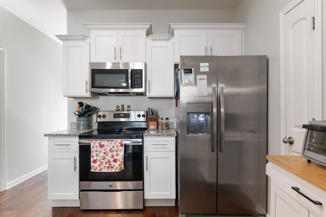 kitchen featuring dark wood-type flooring, white cabinetry, light stone counters, and appliances with stainless steel finishes