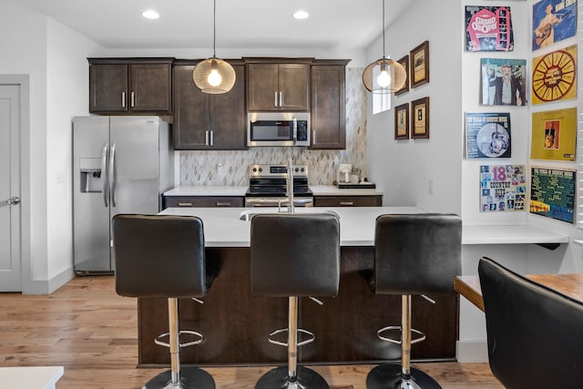 kitchen with stainless steel appliances, hanging light fixtures, and a kitchen bar