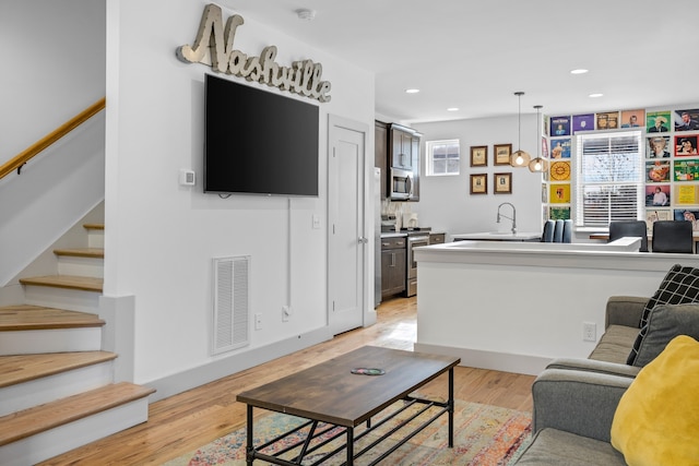 living room featuring sink and light hardwood / wood-style flooring