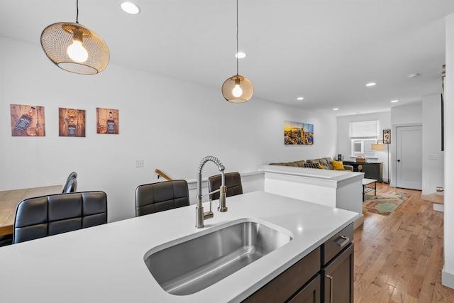 kitchen featuring sink, hanging light fixtures, dark brown cabinets, and light hardwood / wood-style floors