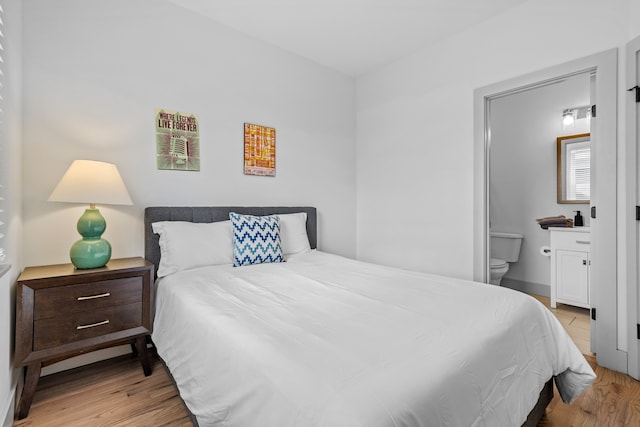 bedroom with light hardwood / wood-style flooring and connected bathroom