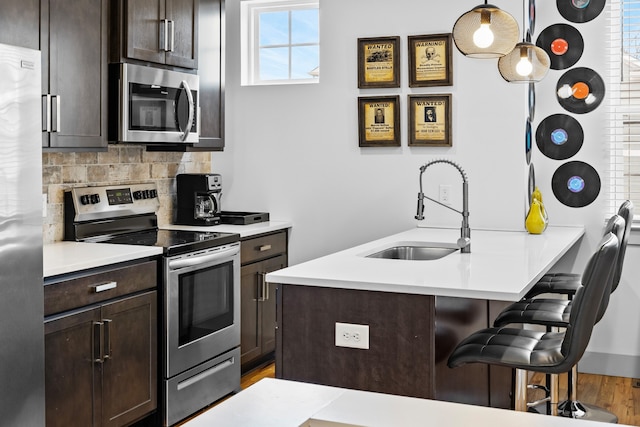 kitchen with a healthy amount of sunlight, appliances with stainless steel finishes, sink, and hanging light fixtures