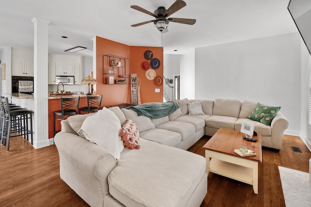 living room featuring sink, ceiling fan, ornate columns, and dark hardwood / wood-style floors