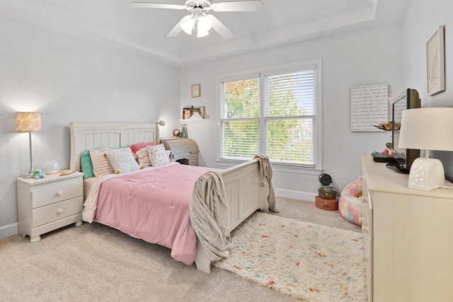 bedroom with light carpet, ceiling fan, and a tray ceiling