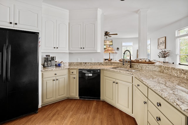 kitchen with black appliances, sink, ornate columns, and light hardwood / wood-style flooring