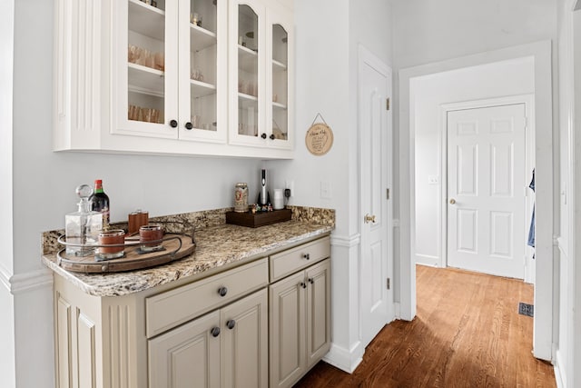 bar with light stone countertops and wood-type flooring