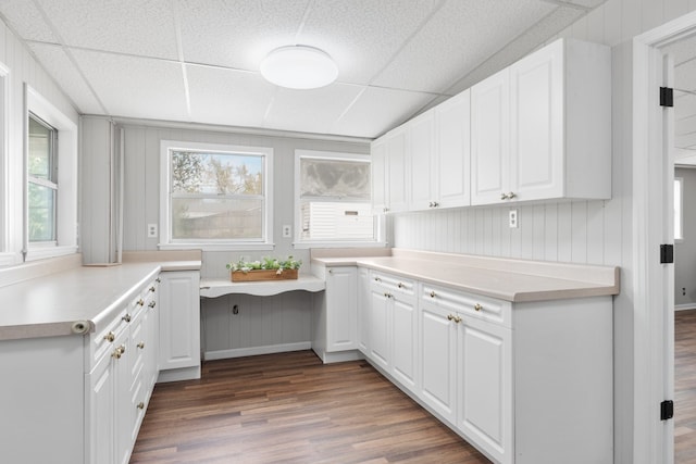 kitchen featuring a drop ceiling, white cabinets, and wood-type flooring