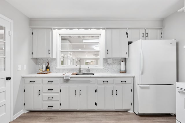 kitchen featuring white appliances, backsplash, sink, and white cabinets