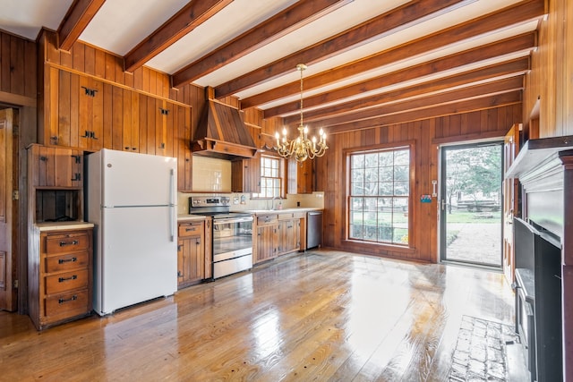 kitchen with light wood-type flooring, custom range hood, stainless steel appliances, beam ceiling, and wood walls