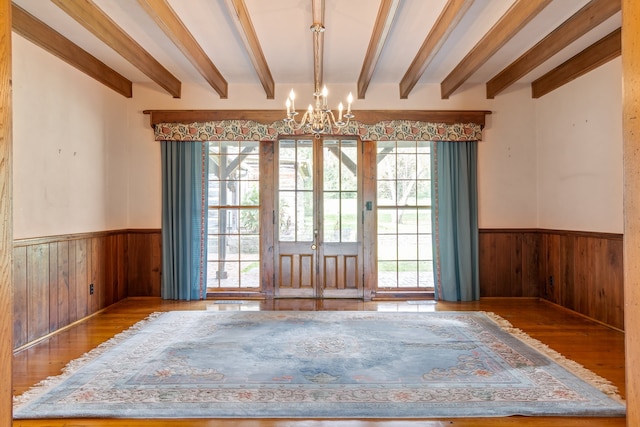 spare room featuring hardwood / wood-style floors, beam ceiling, an inviting chandelier, and french doors