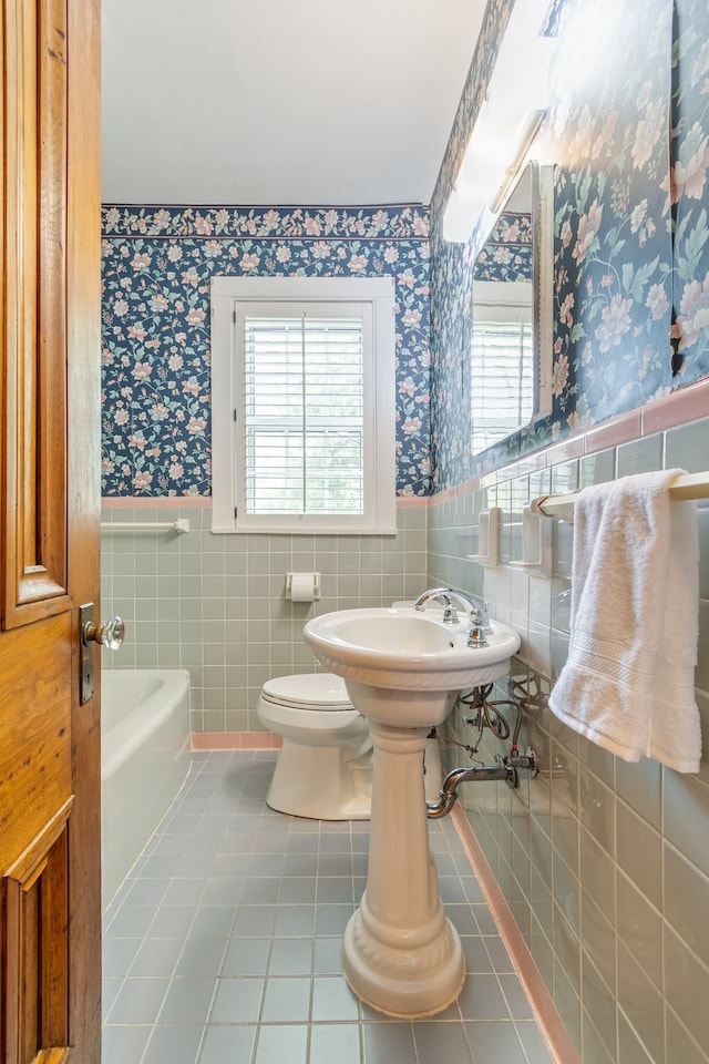 bathroom featuring a tub, a wealth of natural light, and tile walls