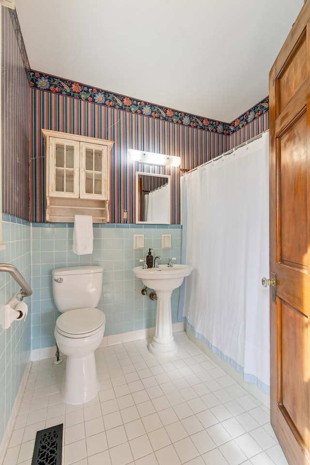 bathroom with tile patterned flooring, a shower with curtain, toilet, and tile walls