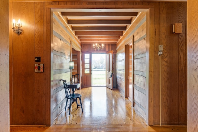 interior space with light hardwood / wood-style flooring, wooden walls, and a notable chandelier