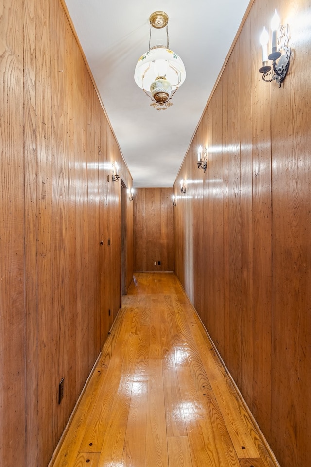 hallway featuring light wood-type flooring and wooden walls