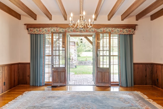 doorway to outside with beam ceiling, wooden walls, a chandelier, and hardwood / wood-style flooring