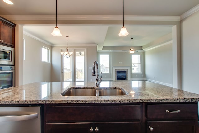 kitchen with crown molding, appliances with stainless steel finishes, sink, pendant lighting, and light stone counters