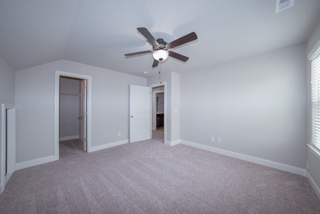 unfurnished bedroom featuring a closet, ceiling fan, light carpet, and a walk in closet