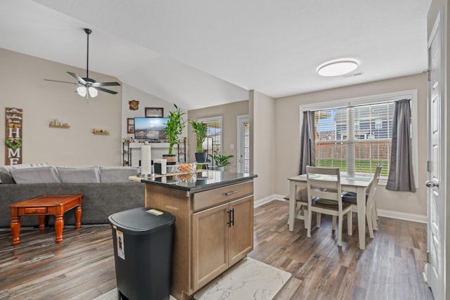 kitchen with lofted ceiling, a kitchen island, wood-type flooring, and ceiling fan