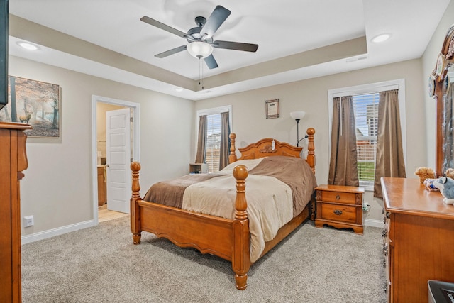 bedroom with a raised ceiling, ceiling fan, and light carpet