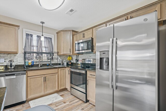 kitchen featuring decorative backsplash, stainless steel appliances, sink, pendant lighting, and light hardwood / wood-style floors