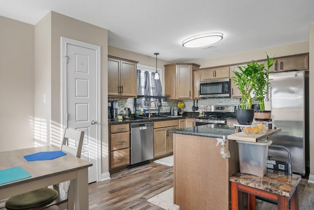 kitchen with appliances with stainless steel finishes, tasteful backsplash, dark wood-type flooring, sink, and decorative light fixtures