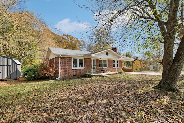 view of front facade featuring a storage shed, an outbuilding, crawl space, a porch, and brick siding