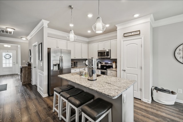 kitchen with a breakfast bar, white cabinets, stainless steel appliances, and hanging light fixtures