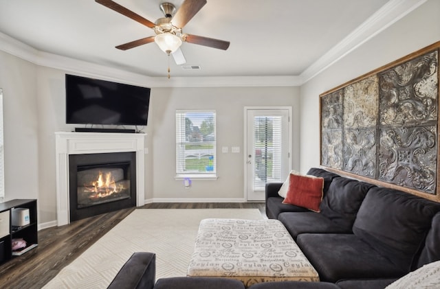 living room with dark wood-type flooring, crown molding, and ceiling fan