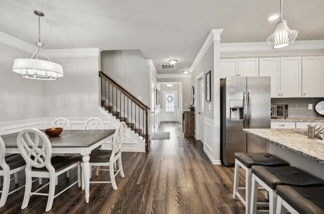 kitchen featuring white cabinetry, light stone counters, hanging light fixtures, and stainless steel fridge with ice dispenser