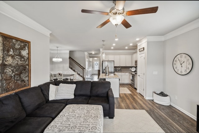 living room featuring crown molding, dark hardwood / wood-style floors, and ceiling fan with notable chandelier