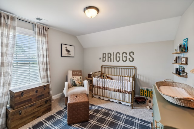 carpeted bedroom featuring lofted ceiling and a crib