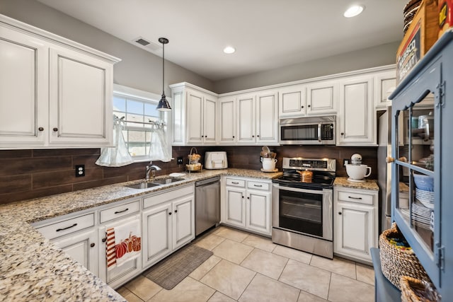 kitchen with light stone countertops, appliances with stainless steel finishes, sink, decorative light fixtures, and white cabinetry