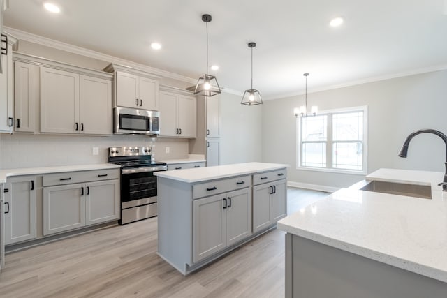 kitchen featuring sink, gray cabinets, a kitchen island, appliances with stainless steel finishes, and decorative light fixtures