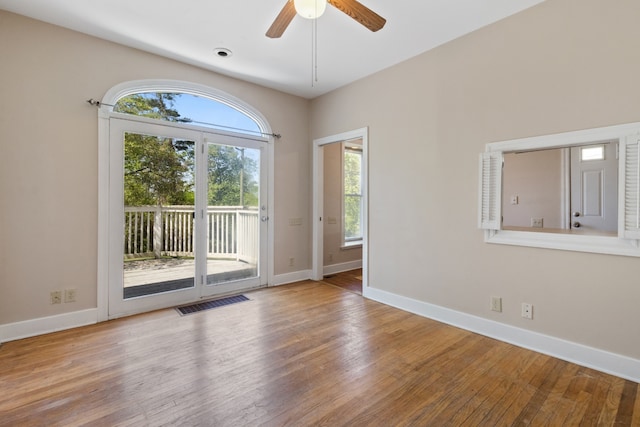 unfurnished room featuring a wealth of natural light, hardwood / wood-style floors, and ceiling fan