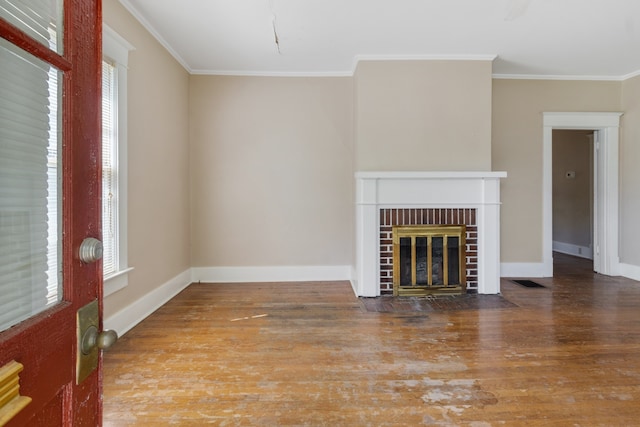 unfurnished living room with crown molding, a brick fireplace, wood-type flooring, and a healthy amount of sunlight