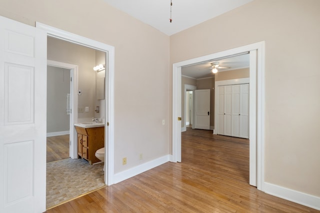 hallway with sink, ornamental molding, and light hardwood / wood-style flooring